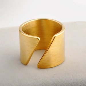 Detailed macro view of gold-tone wide band ring with brushed matte finish and geometric cut