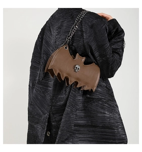 Detail of a dark brown bat-shaped jelly bag with black metal chain and skull decoration