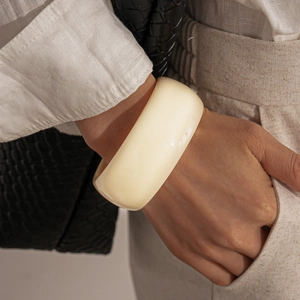 Close-up of wide chunky acrylic bangle in cream ivory color worn on wrist