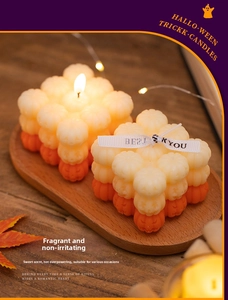Close-up of orange pumpkin scented candles with silk ribbon on a rustic wooden tray