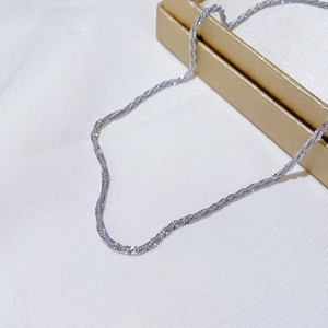 Macro view of silver twisted rope chain necklace with a metallic glossy finish on a grid background