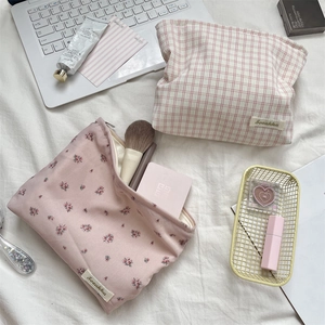 Close-up of floral and plaid makeup bags on a desk with beauty tools and accessories