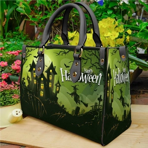 Green and black Halloween tote bag with witch and haunted house print in a garden