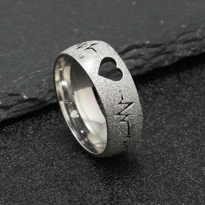 Silver heartbeat ring with frosted finish and hollow heart design on slate background