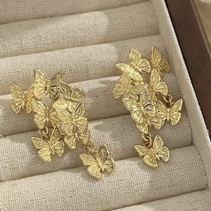 Elegant gold butterfly drop earrings with hollow wings on a velvet jewelry box display