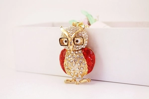 Vue détaillée du porte-clés hibou doré avec strass et détails en émail rouge vif