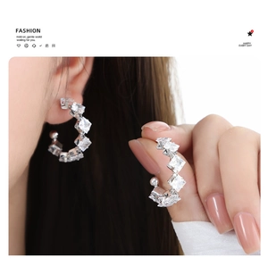 Detail of C-shaped 18K gold plated earrings with sparkling square cubic zirconia crystals