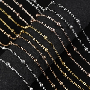 Detailed view of gold, silver, and rose gold flat cross beaded chains on a black display
