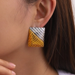 Close-up of a square two-tone gold and silver earring with textured wavy surface