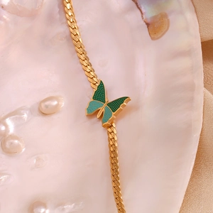 Detail view of a 18K gold-plated flat NK chain with a green butterfly pendant and pearls