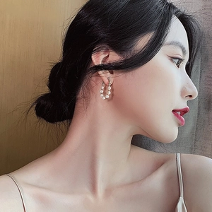 Elegant gold hoop earrings with small freshwater pearls worn by model in soft light