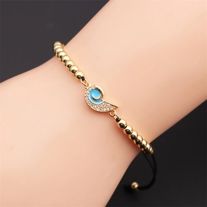 Detail of gold-plated braided bracelet with blue enamel and white zircon inlay on wrist
