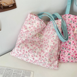 Close-up of pink floral quilted fabric and blue ribbon handle on a shoulder tote bag