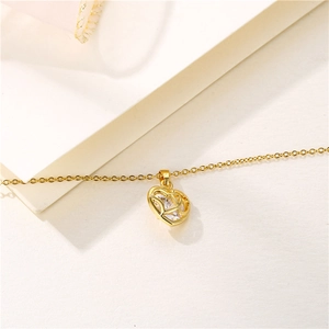 Collier élégant doré avec pendentif cœur ajouré et zircon clair sur fond en pierre blanche