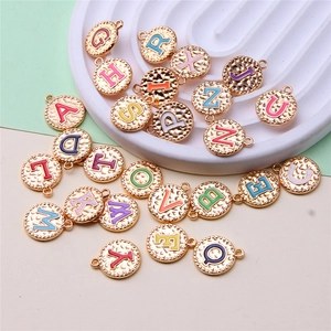 Macro detail of round gold metal alloy pendants with colorful A-Z letters on tray