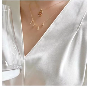 Detail of gold double-layered necklace featuring H-letter pendant and 1988 crystal numbers