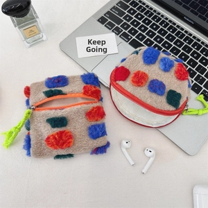 Macro shot of plush storage pouch with colorful pompoms and neon lanyards on desktop