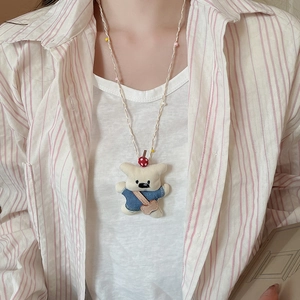 Detailed view of handmade teddy bear pendant with blue sweater and colorful beaded cord