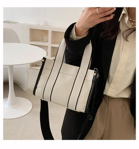 Close-up of canvas tote bag with black strap detail and gold-tone metal hardware