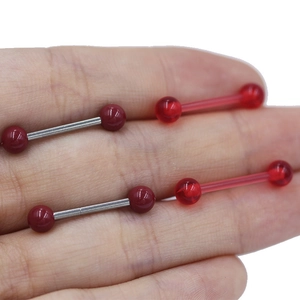 Detail of red heart zircon nipple ring featuring a stainless steel barbell and resin finish