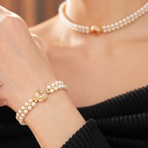Gros plan d'un bracelet et collier en perles double rang avec fermoir doré et gemme rose