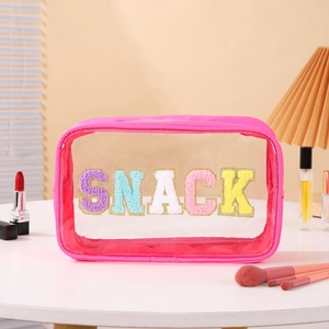 Detail of pink transparent cosmetic bag with colorful SNACK towel embroidery and gold zipper