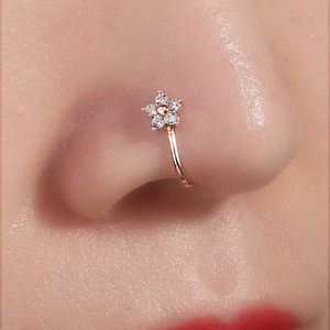 Detailed close-up of a golden flower nose ring with sparkling crystals on skin