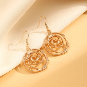 Exaggerated gold swirl rose earrings set on elegant silk fabric background