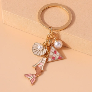 Detail view of mermaid and shell enamel charms with a pearl on a golden keychain