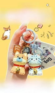 Detail of Shiba Inu and tabby cat charms with wood-carved texture and golden bells
