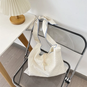 Détail du sac en toile à pois blancs avec bordure bleue et bandoulière à nœud réglable
