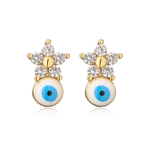 Detailed view of gold flower earrings with zircon and evil eye enamel pendants on white