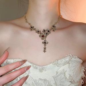 Vintage gold necklace featuring floral patterns with deep red gems on model's neck