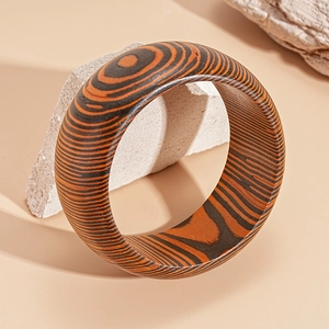 Macro detail of geometric wood grain bangle with warm brown textures on white stone