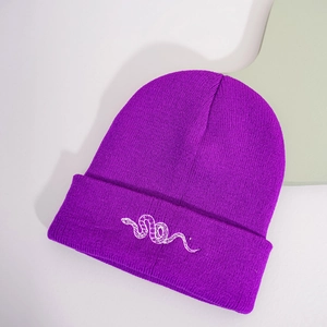 Detail view of the purple knit beanie featuring white snake embroidery on the folded cuff