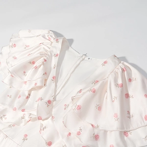 Détail du col en V avec imprimé floral rose et volants superposés sur robe en mousseline