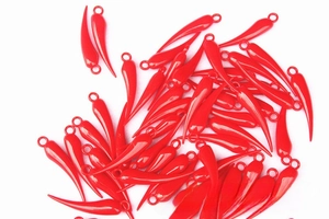 Macro shot of glossy red chili pendants with top ring for DIY jewelry and New Year decor
