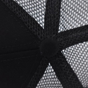 Macro shot of the top button and stitched seams on a black mesh baseball trucker cap
