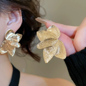 Detail of gold textured petal earrings showing layered metal leaves on model