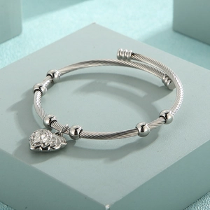 Detailed close-up of a silver twisted wire cable bracelet with heart pendant and beads