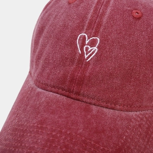 Gros plan sur la casquette en coton délavé bordeaux avec broderie double cœur