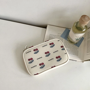 Large capacity canvas makeup bag with cherry print and zipper on white surface