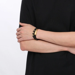 Close-up of men's multilayer braided black leather bracelet with gold metal bar on wrist