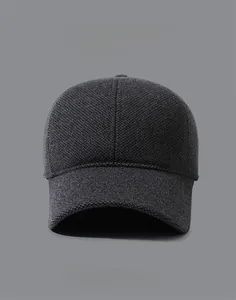 Close-up of gray winter baseball cap with knit texture and metal letter T decoration
