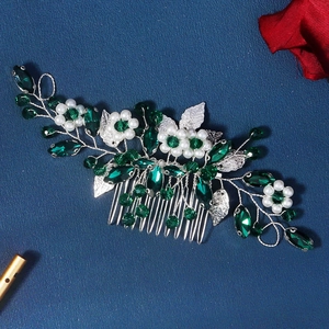 Macro detail of silver bridal hair comb with emerald crystals and faux pearls decor