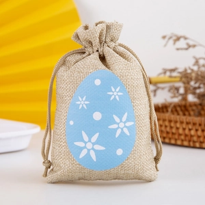 Close-up of a beige linen drawstring gift bag with a blue floral egg-shaped felt patch