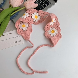 Close-up of pink crochet headband featuring white daisy patterns and woven texture