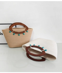 Close-up of woven tote bags in beige and white with wooden handles and turquoise beads