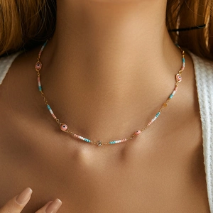 Detail shot of a bohemian beaded necklace with pink evil eye charms on a model neck