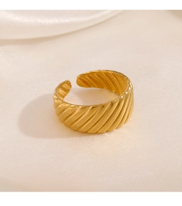 Detailed close-up of a gold croissant ring with ribbed texture on silk background